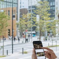福岡の街並みと店舗情報を表示したスマートフォンによるChatGPT検索のイメージ