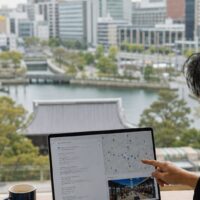 福岡 LLMO 店舗集客をイメージした、AI検索と店舗マーケティングを示すノートパソコン画面と福岡の街並み